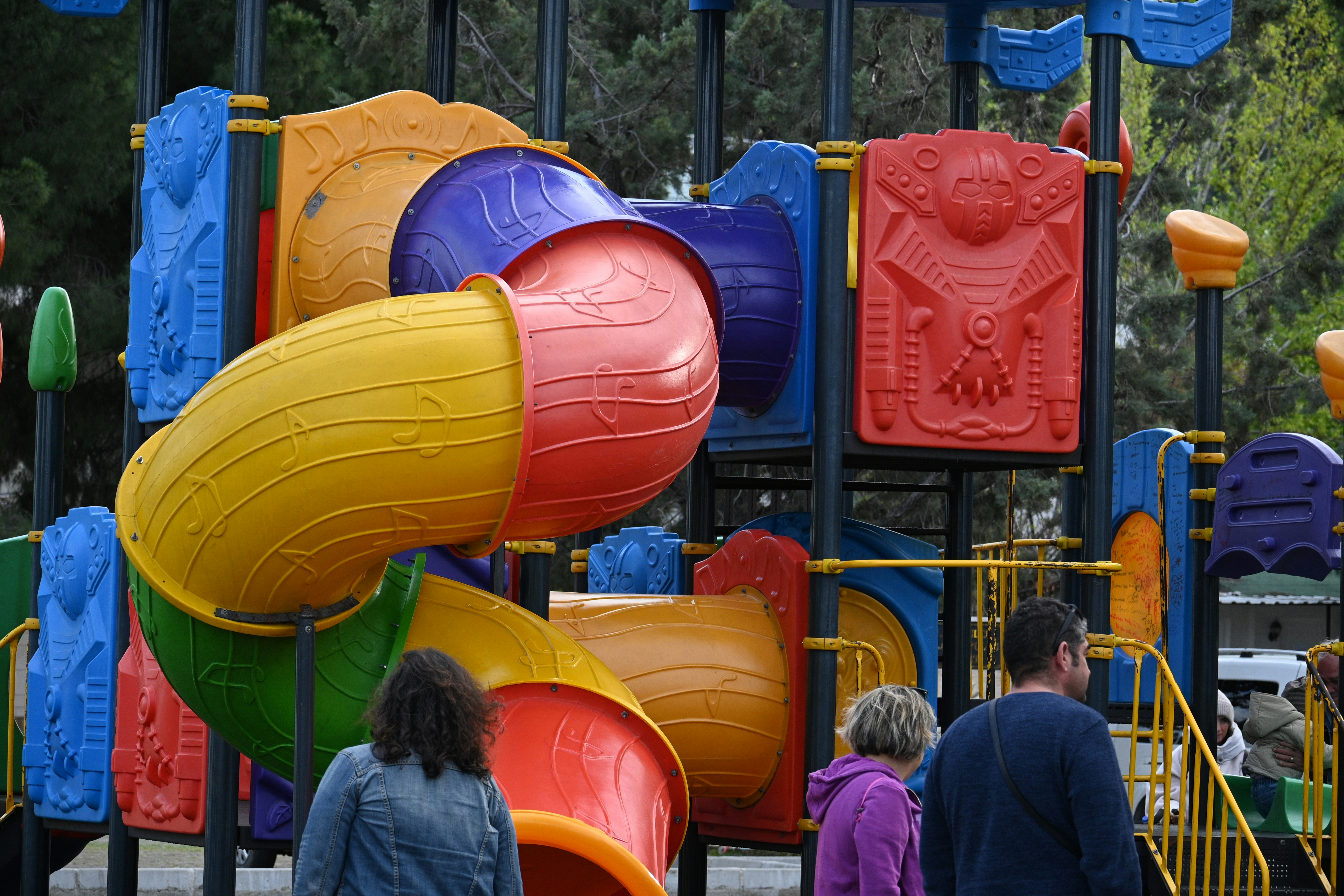 A colorful playground with slides and people.