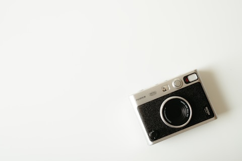 A vintage camera sits on a white surface.