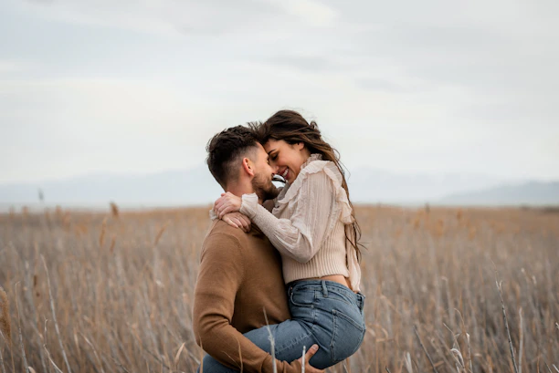 A man holds a woman in a field.