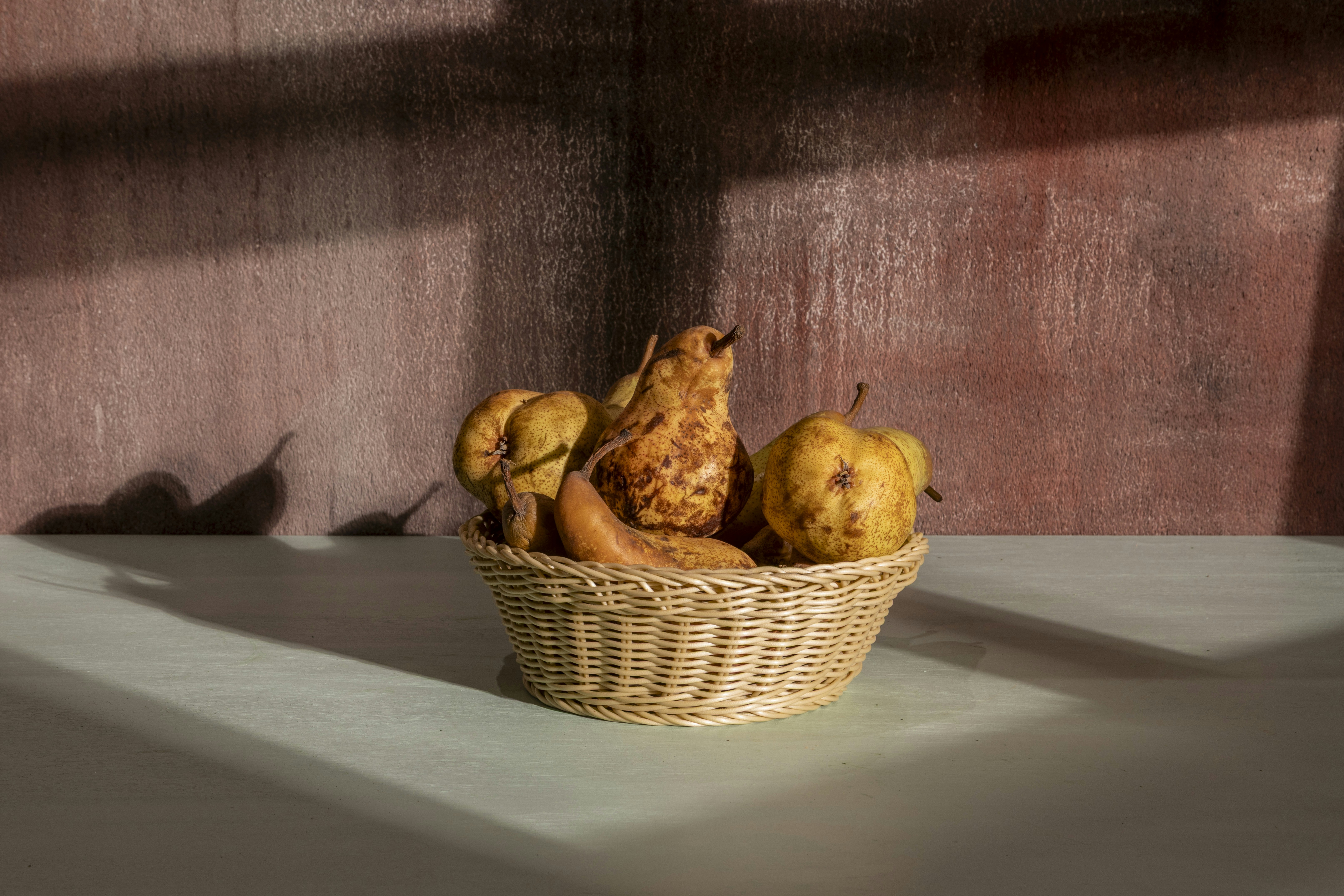 Pears rest in a wicker basket.