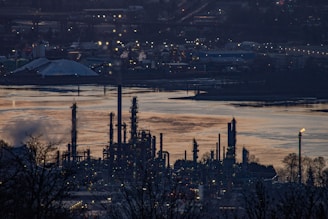 Oil refinery by a river at dusk.