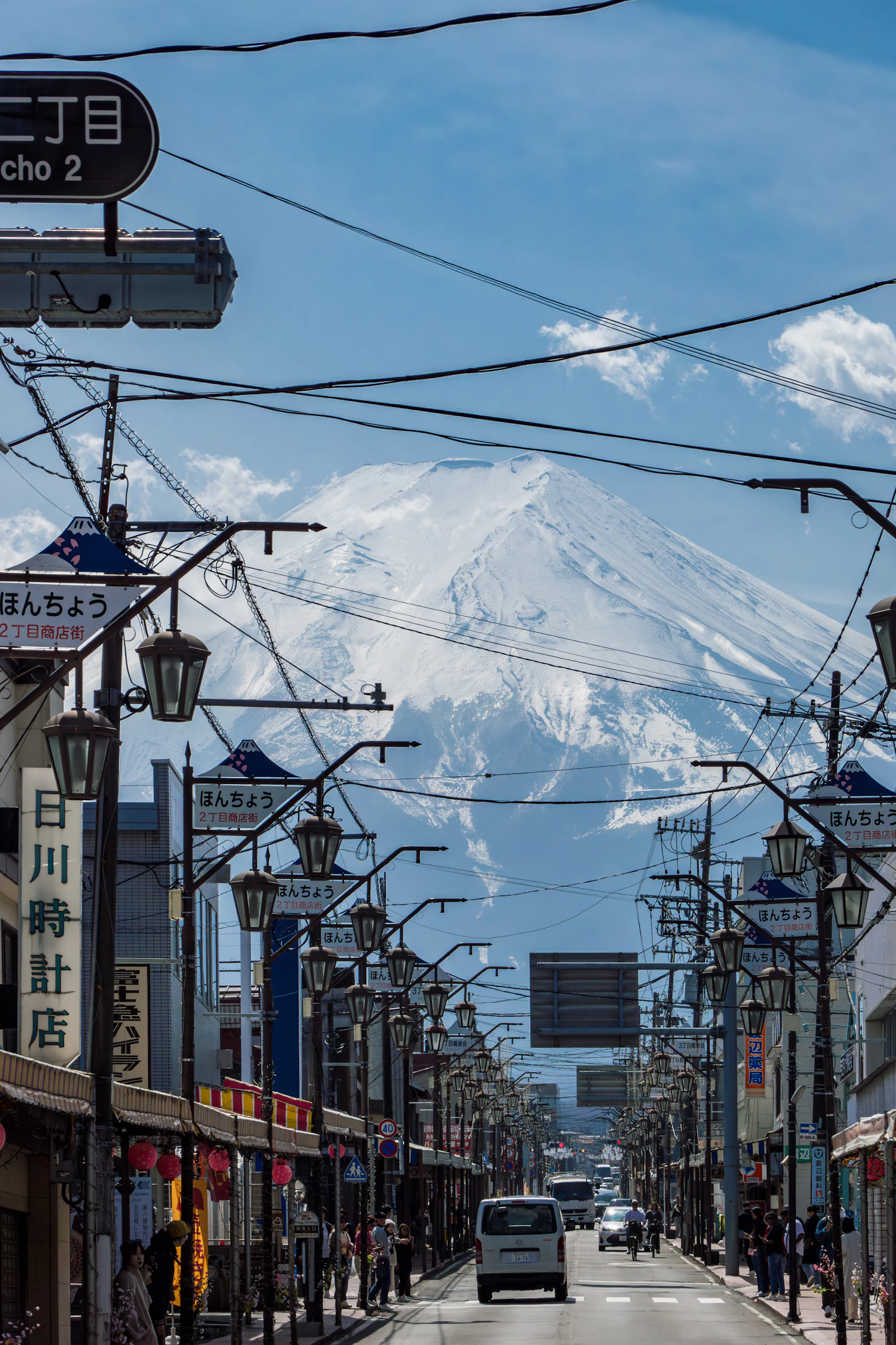 A Japanese street leading toward Mount Fuji with a car in the foreground