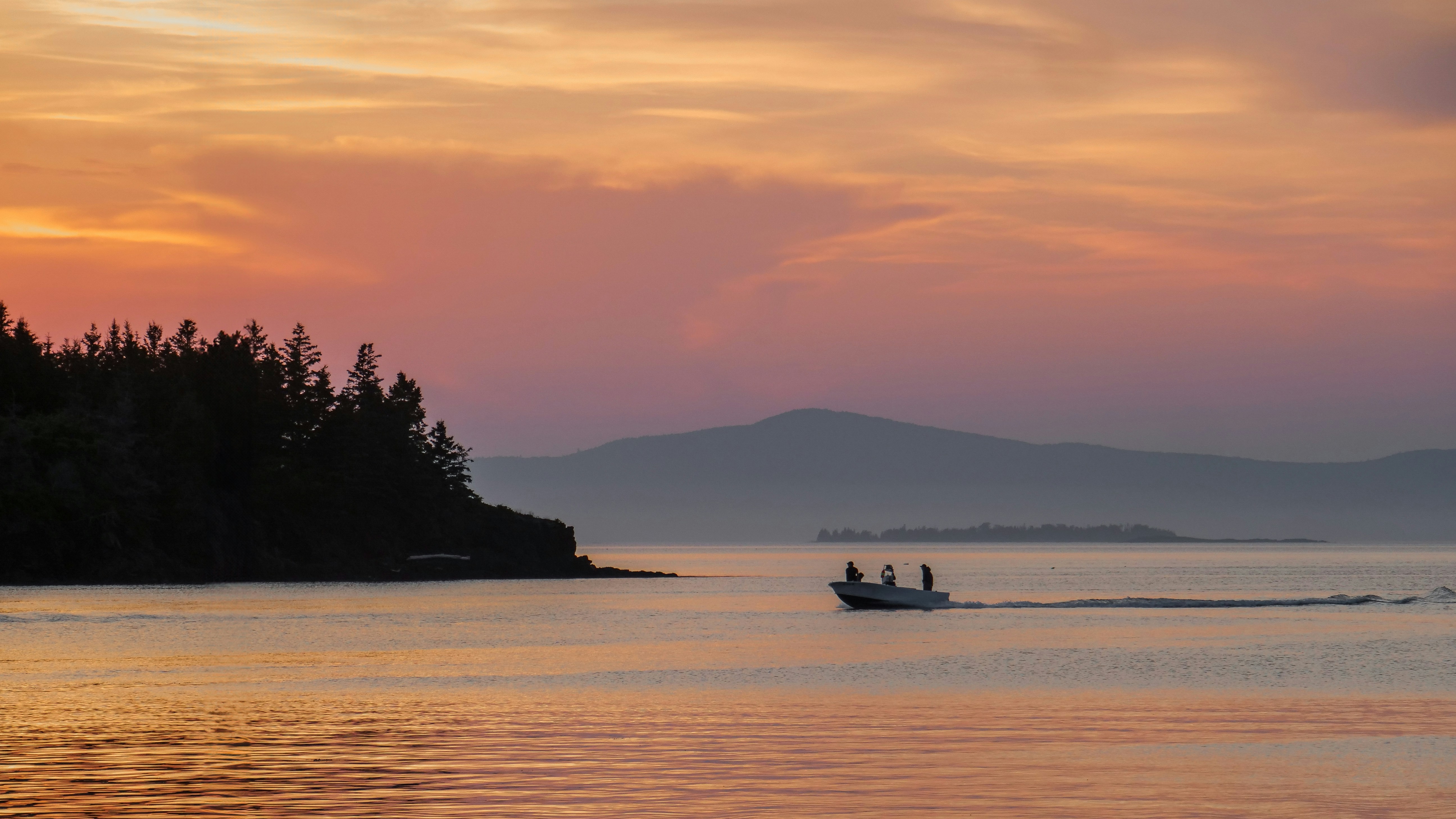 Boat cruises on the water during a beautiful sunset.