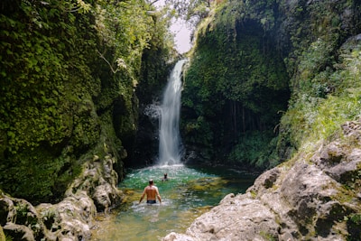 People swim in a refreshing waterfall.