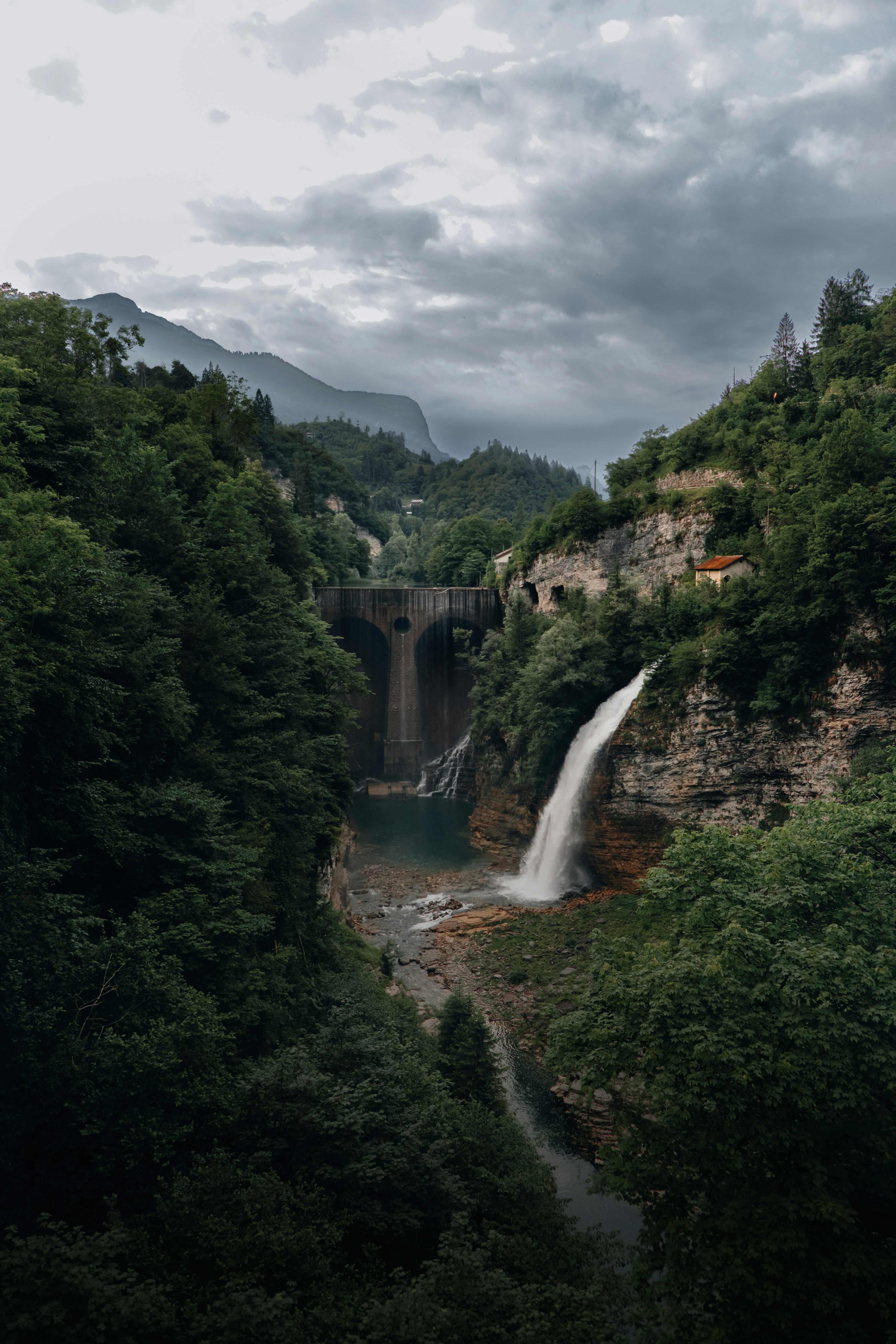 A waterfall cascades below a dramatic dam.