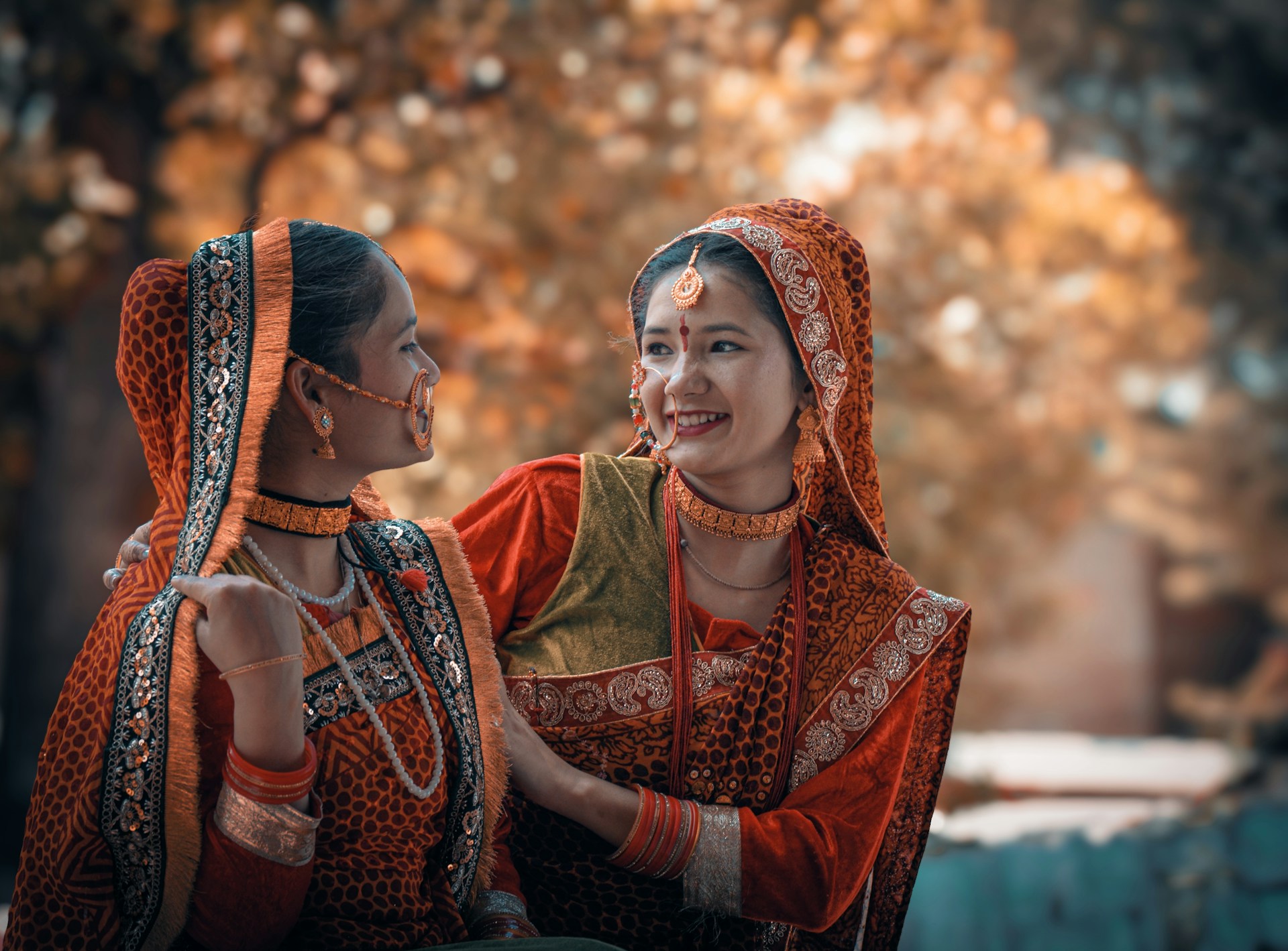 Two women smile and wear traditional clothing.