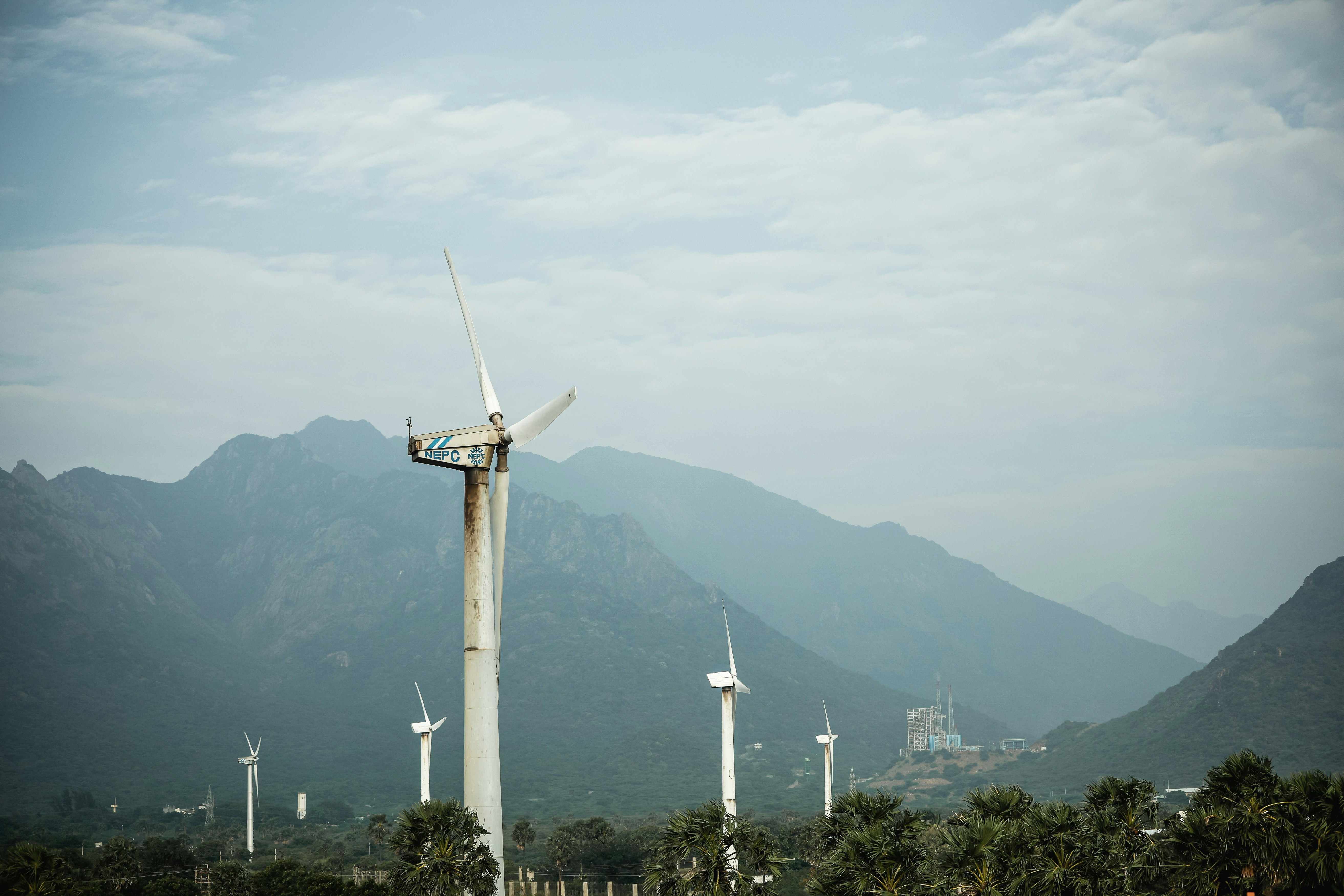 Wind turbines stand tall against a mountain backdrop.