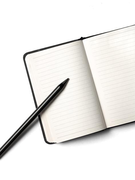 A notebook with a pencil resting on top, photographed against a clean white background