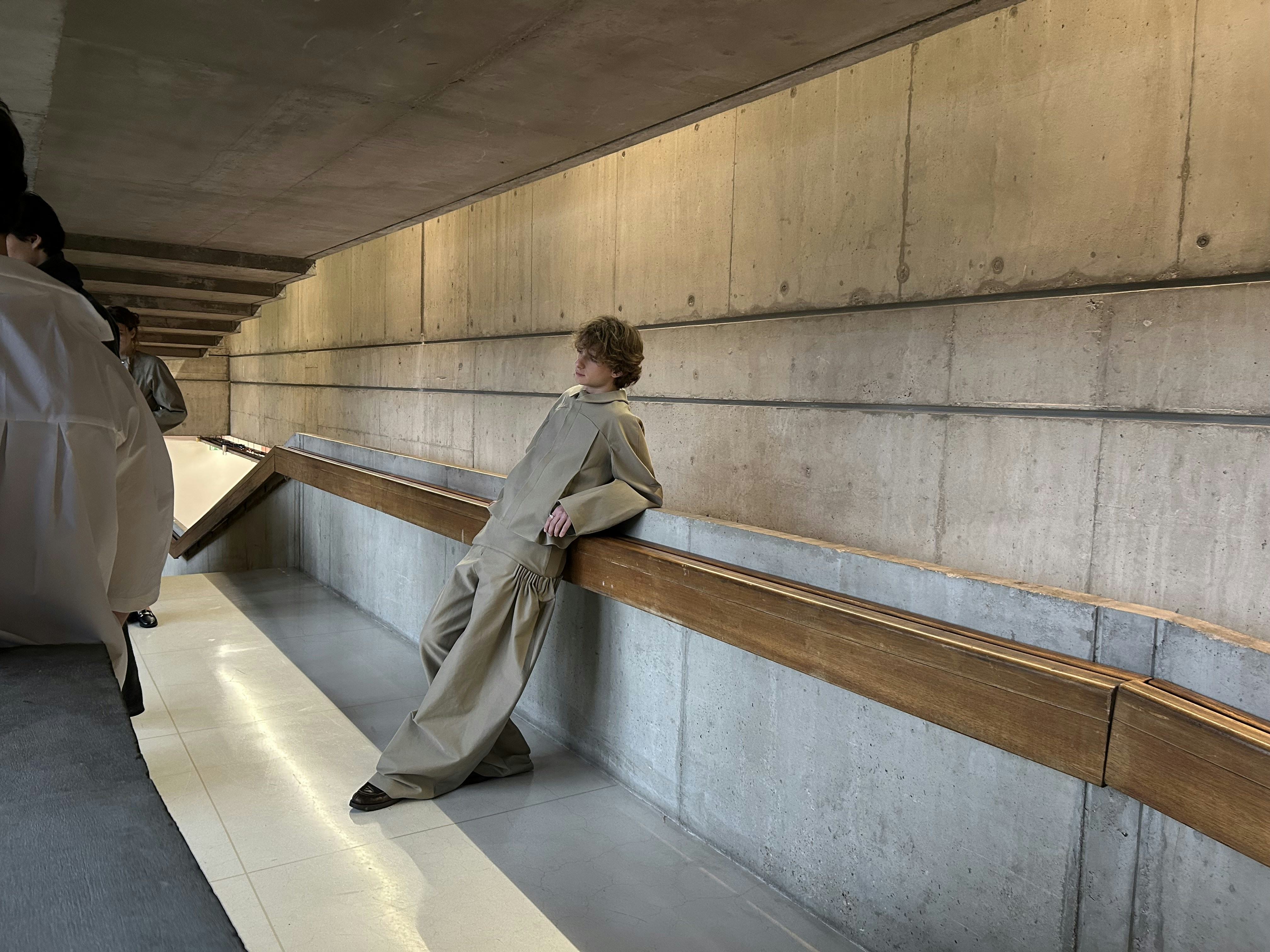 A person leans against a wooden railing.