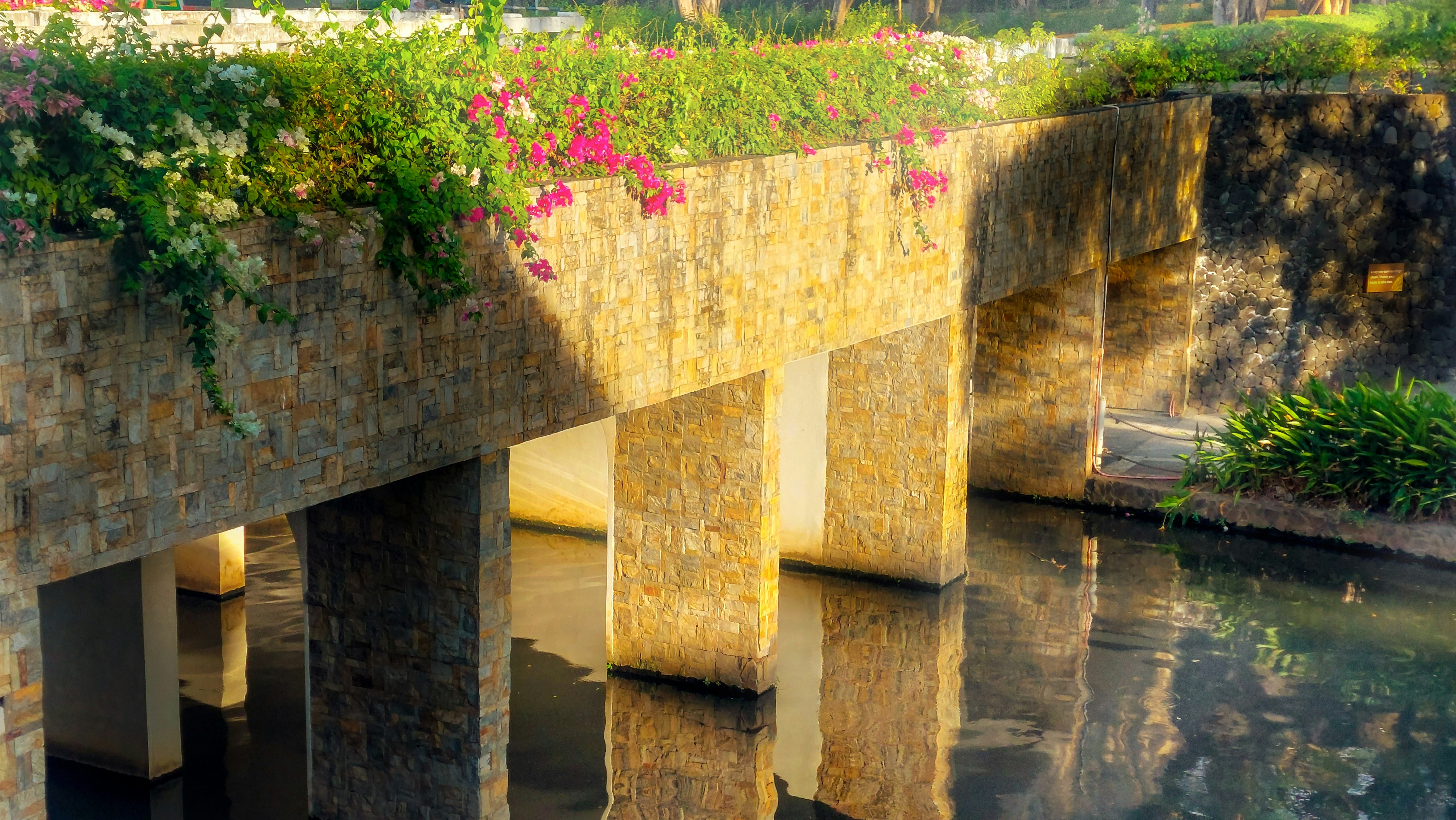 Stone bridge arches over a calm body of water.