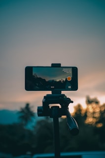 Phone recording a sunset scene on a tripod.