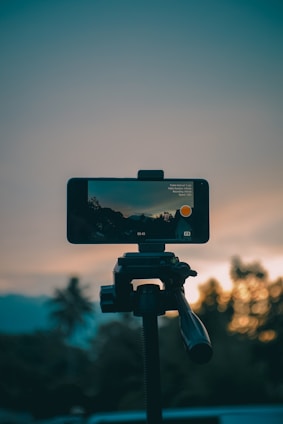 Phone recording a sunset scene on a tripod.