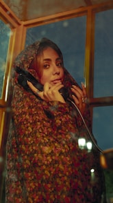 A woman in a phone booth is making a call.