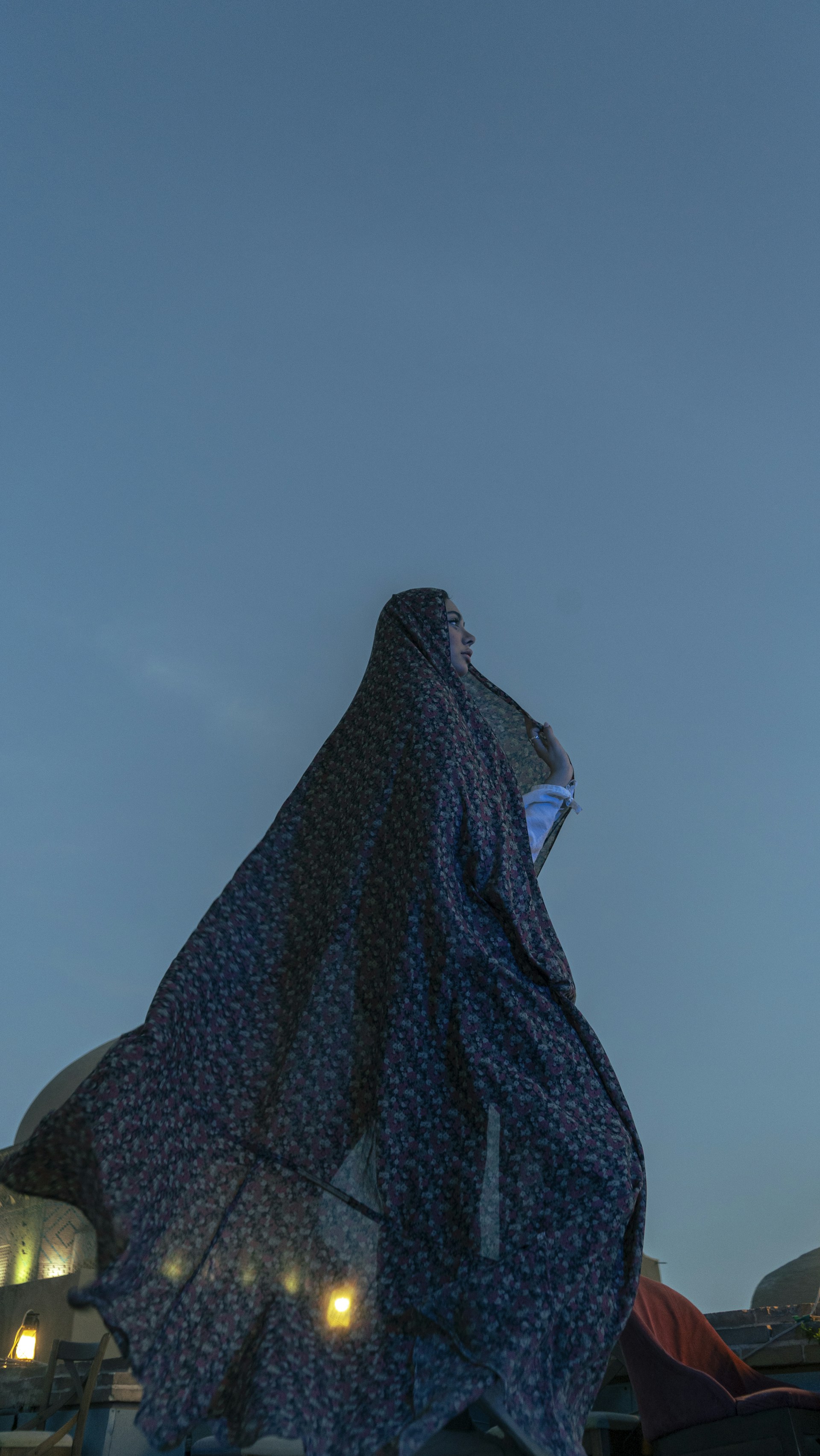 A woman wears a veil in front of the sky.