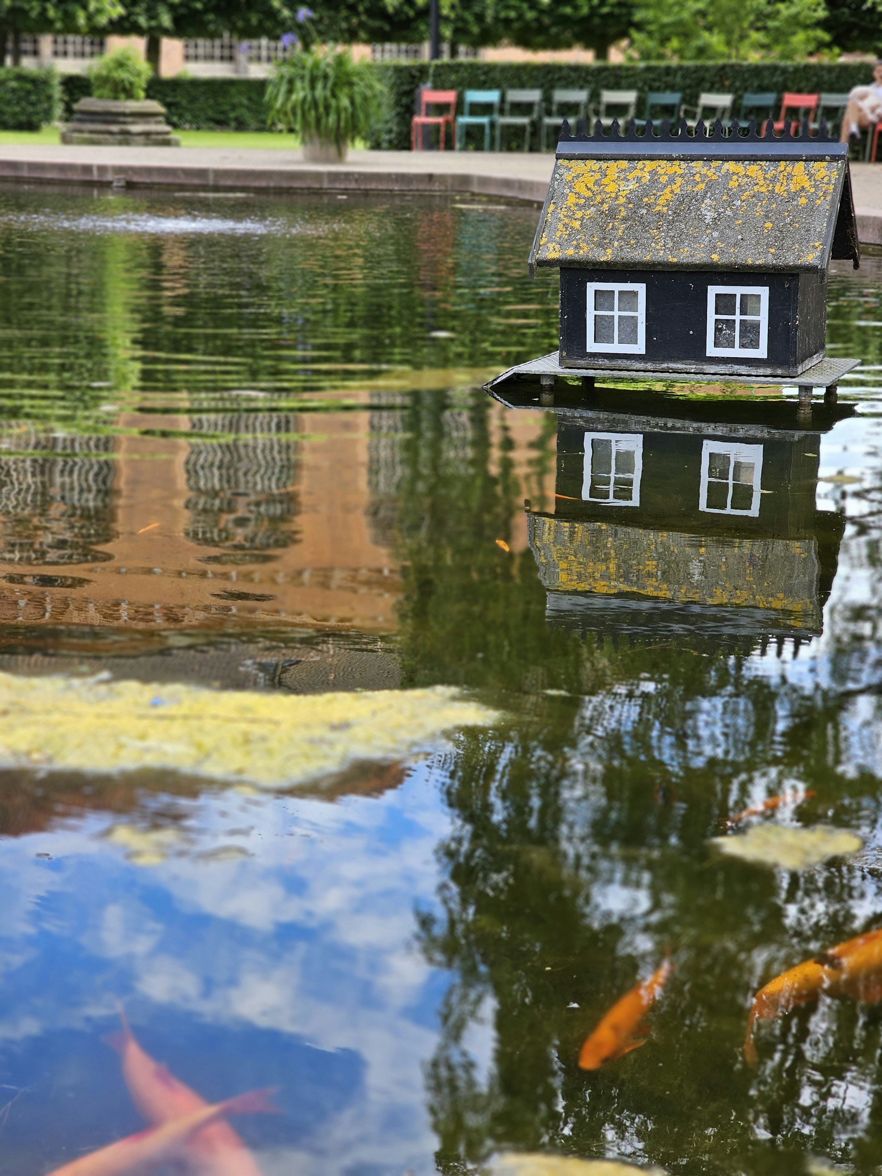 Una pequeña casa flota sobre un estanque con reflejos.