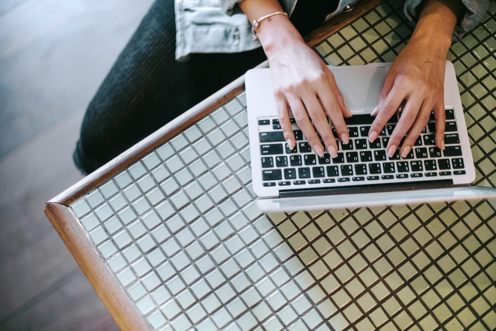 Person types on a laptop on a checkered table.