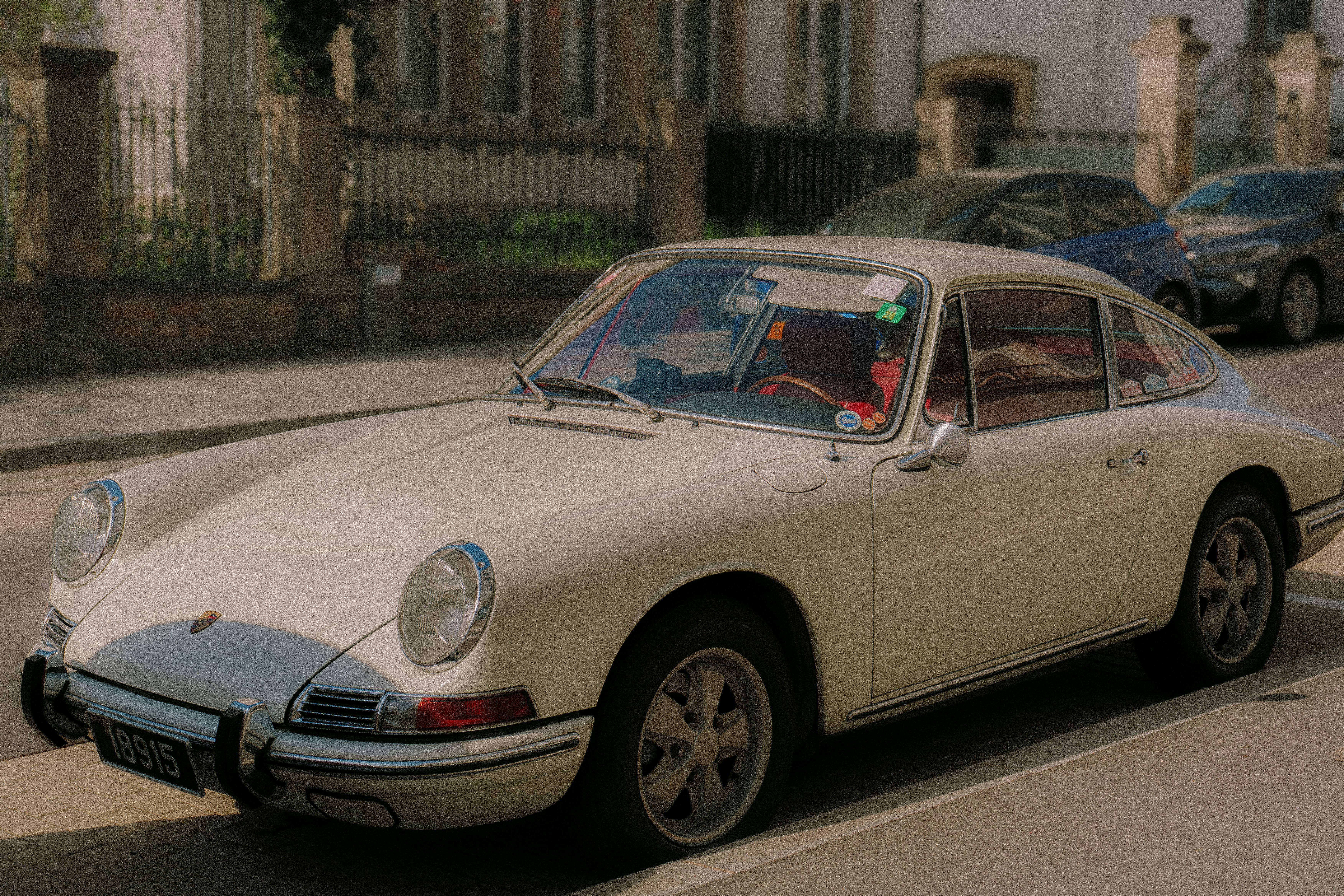 A vintage white porsche is parked on the street.