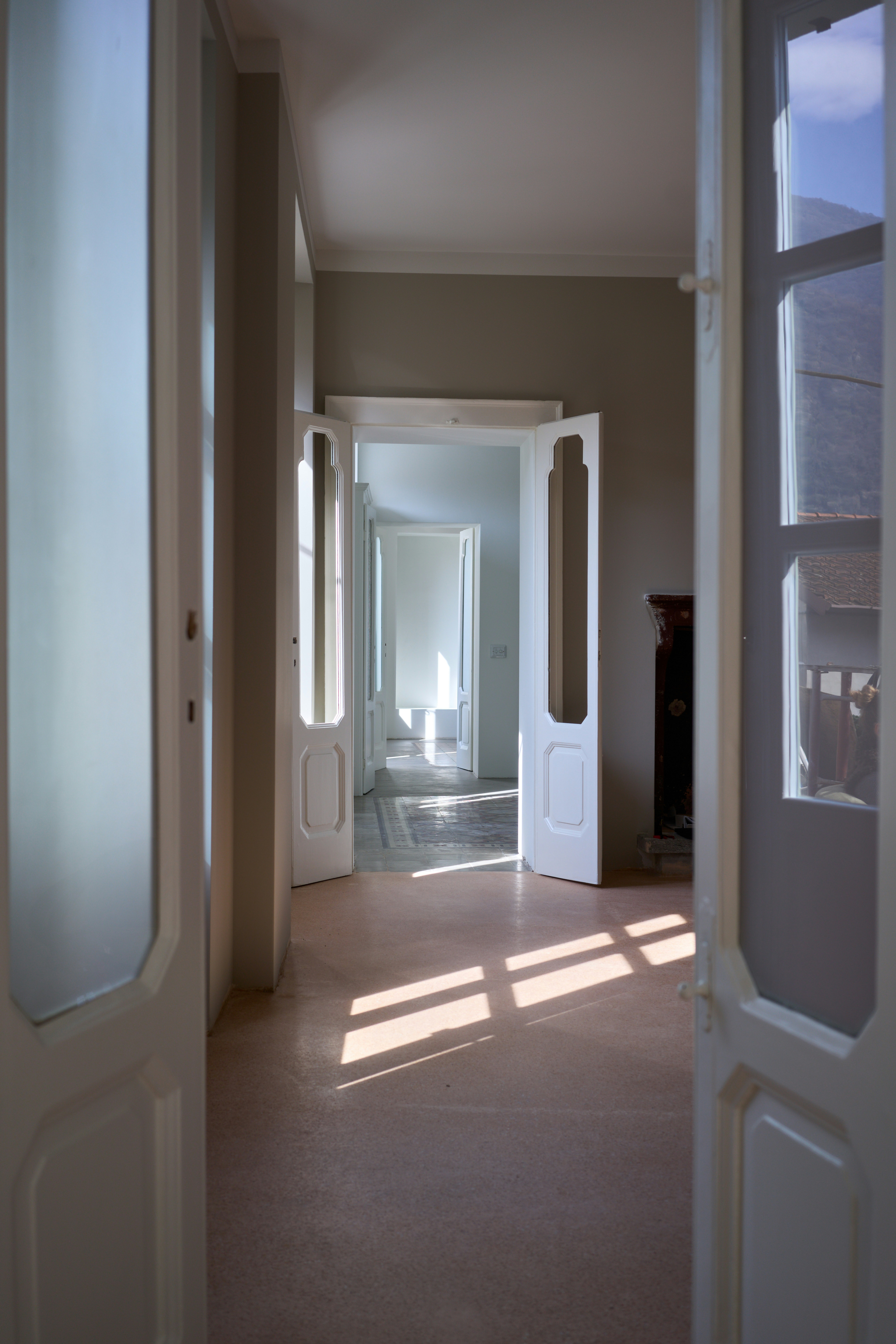 Bright hallway with multiple doorways and sunshine.