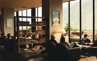 People socialize in a cozy, library-like room.