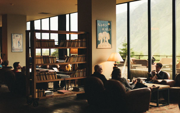 People socialize in a cozy, library-like room.