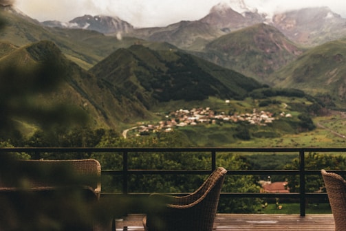 Mountains and a village are viewed from a patio.