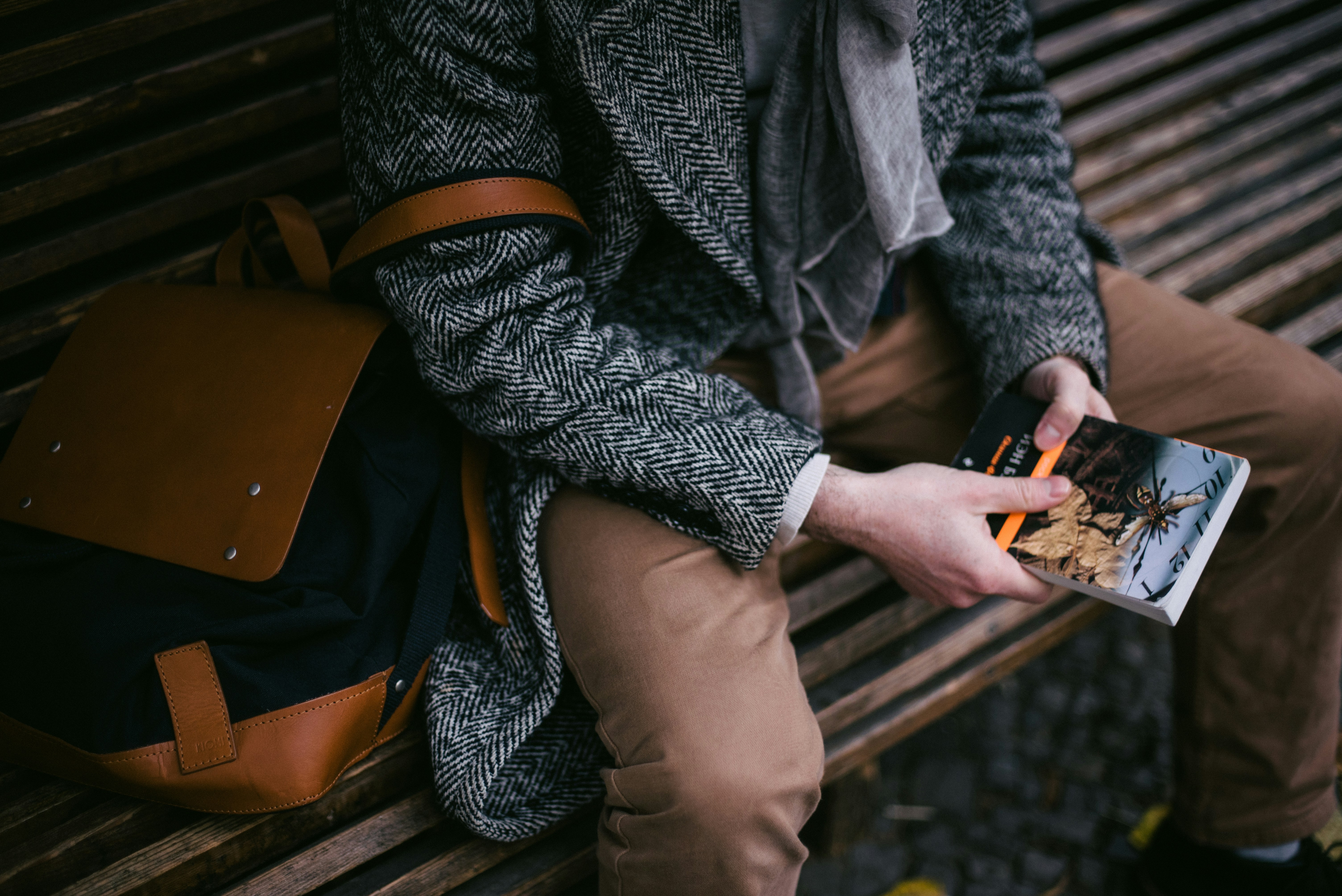 A person reads a book while sitting on a bench.