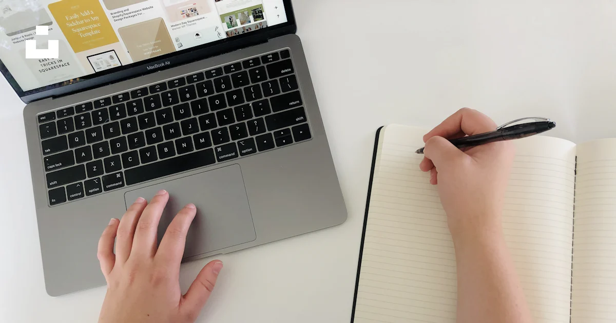 Person is working on a laptop and writing in a notebook. photo – Free ...