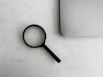 Magnifying glass sits near a laptop on a table.