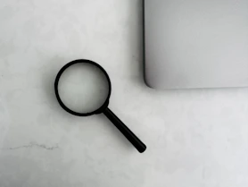 Magnifying glass sits near a laptop on a table.