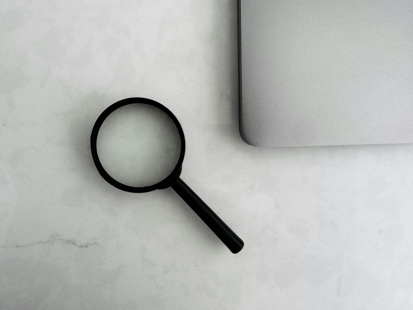 Magnifying glass beside a laptop, representing careful verification