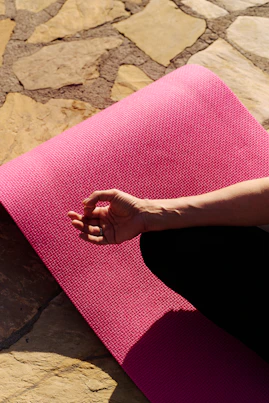 A hand rests on a pink yoga mat.