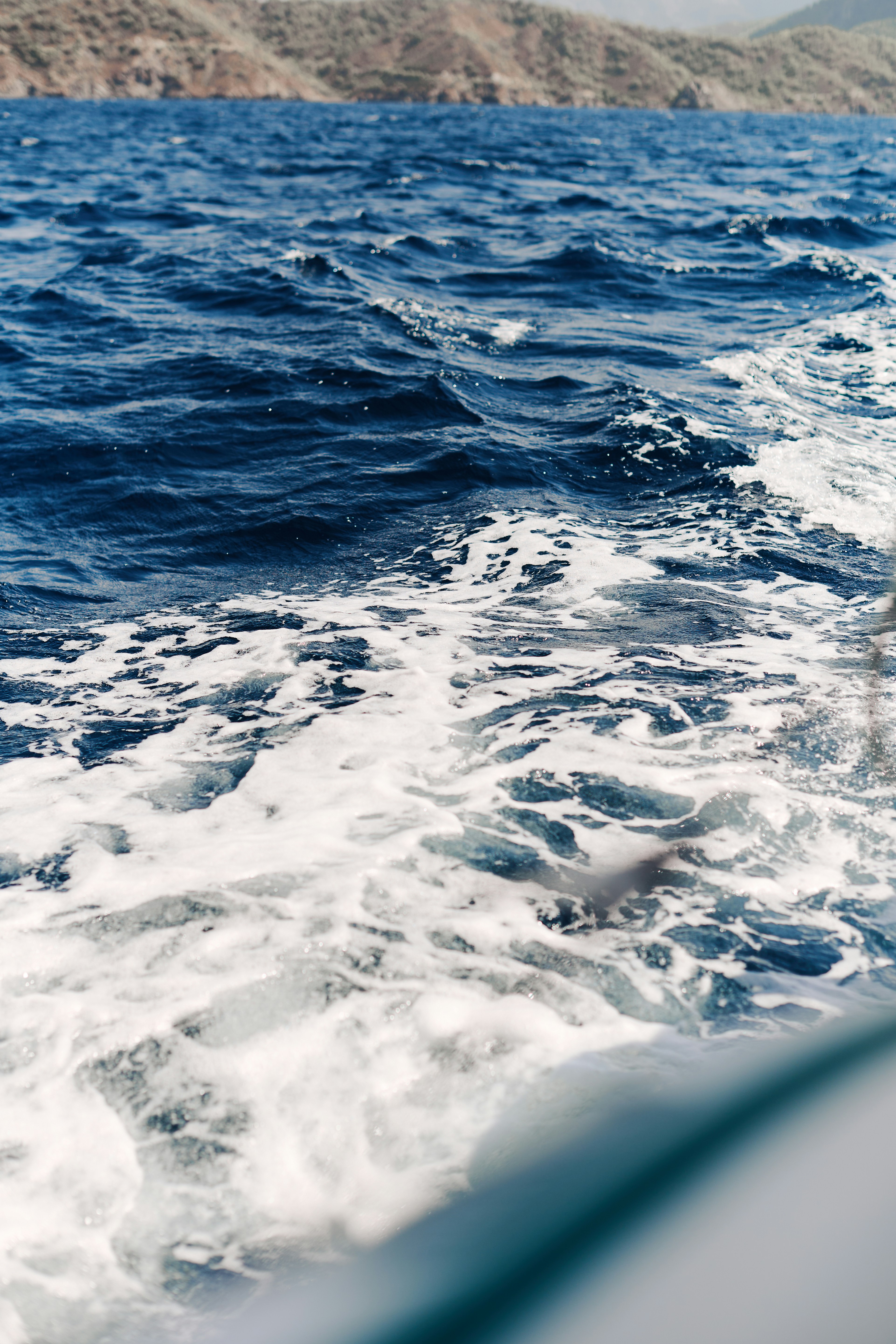 Waves crash on the water, mountains in the distance.