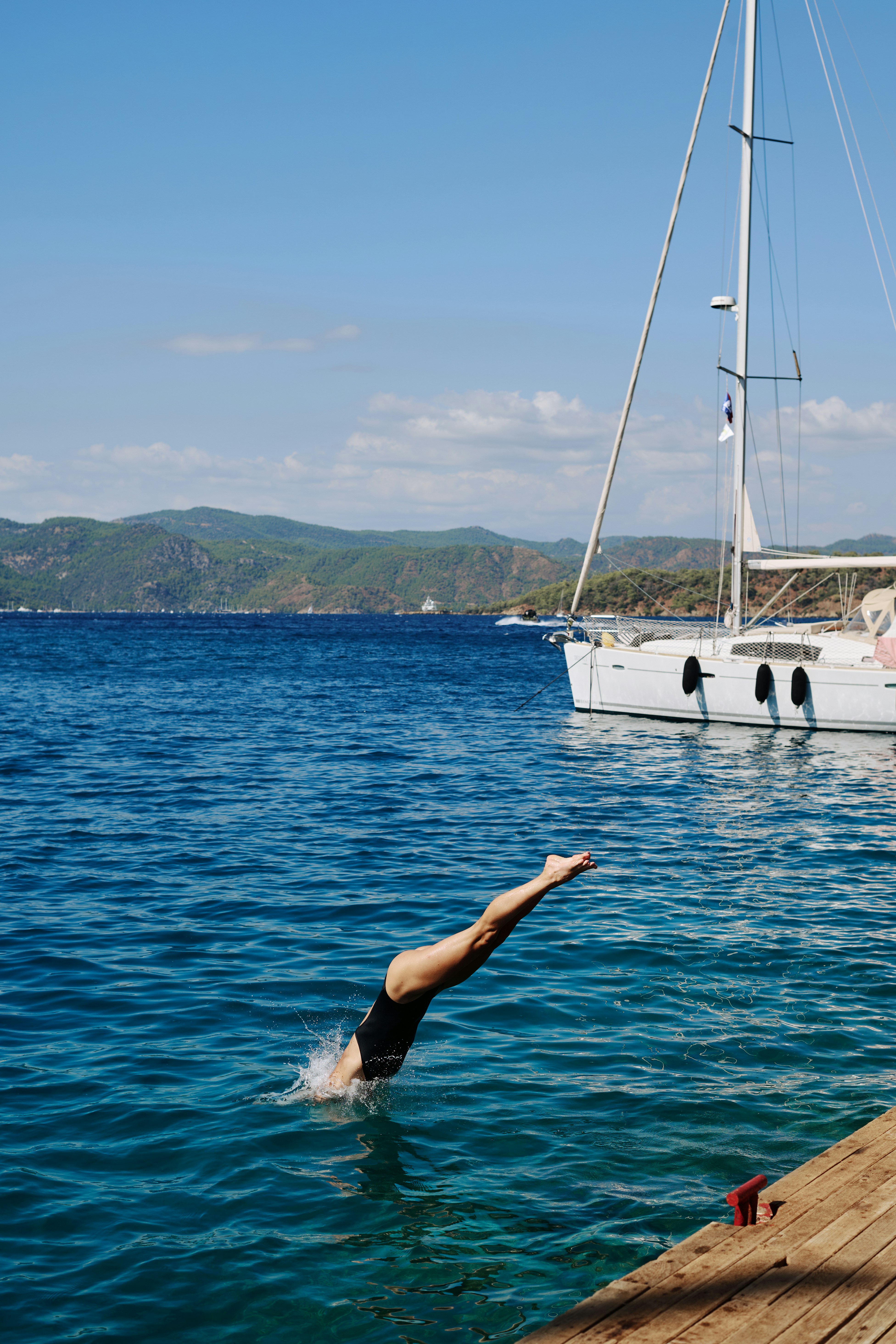 Woman dives into the ocean, with a boat nearby.