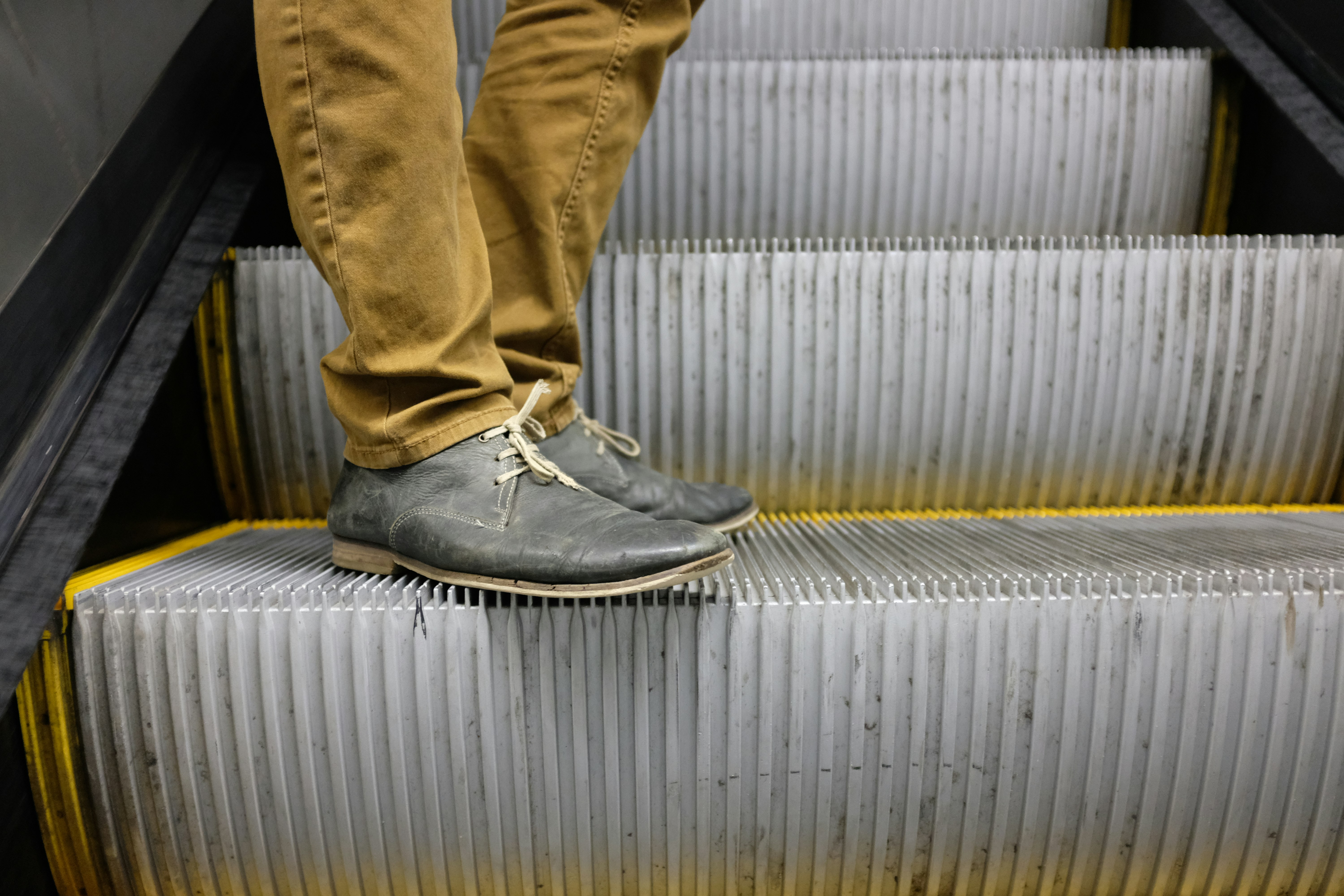 Man's feet stand on the escalator.