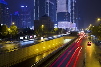 Nighttime cityscape with light trails and skyscrapers.
