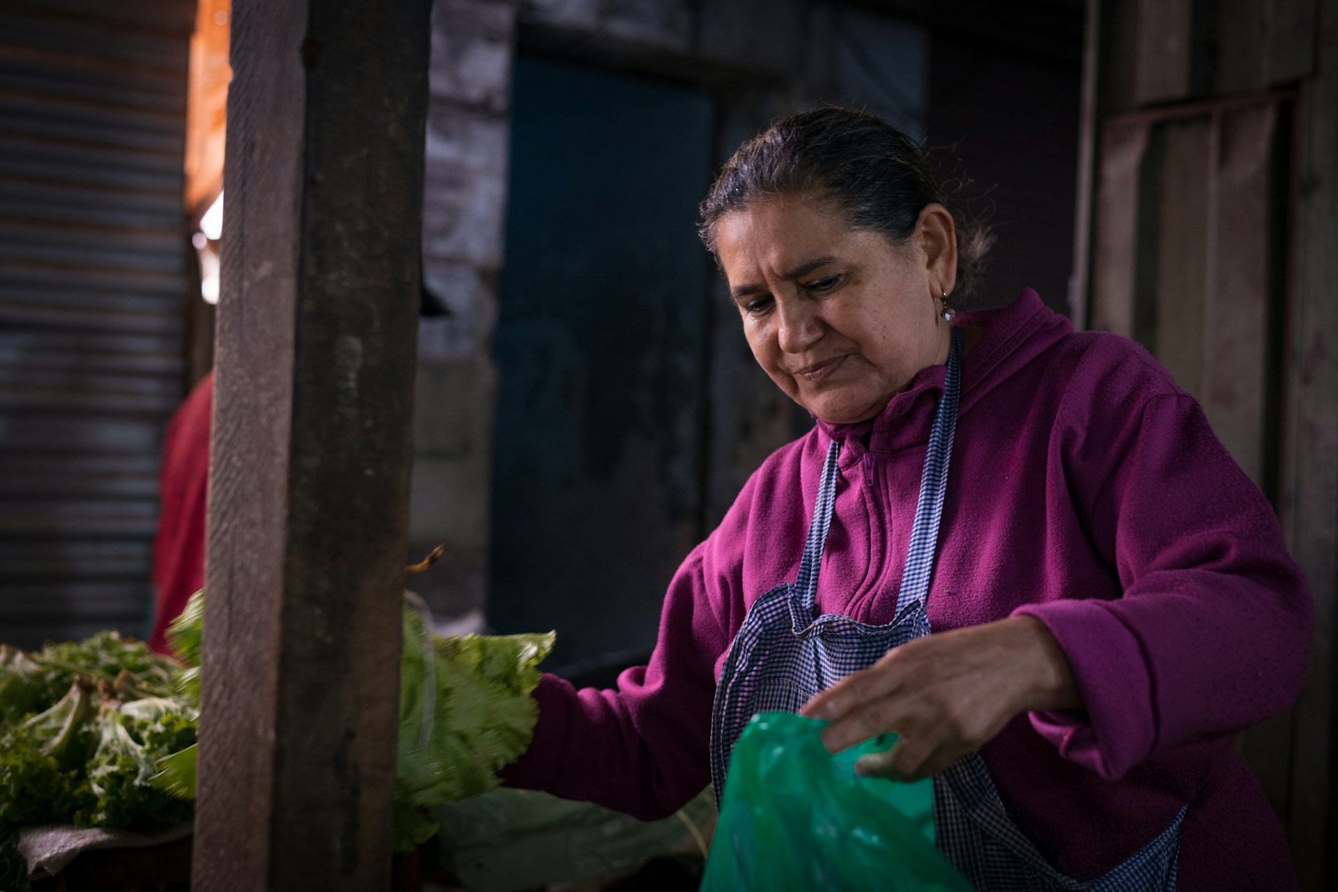 A woman arranges lettuce at a market.