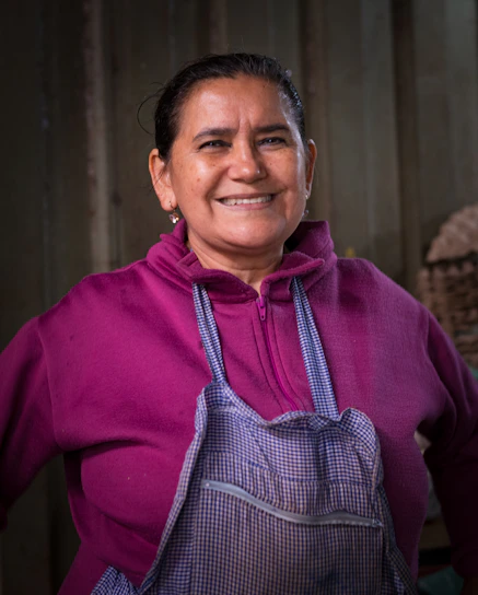 Smiling woman wearing a purple hoodie and apron.