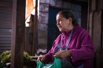 Woman at a market prepares produce.