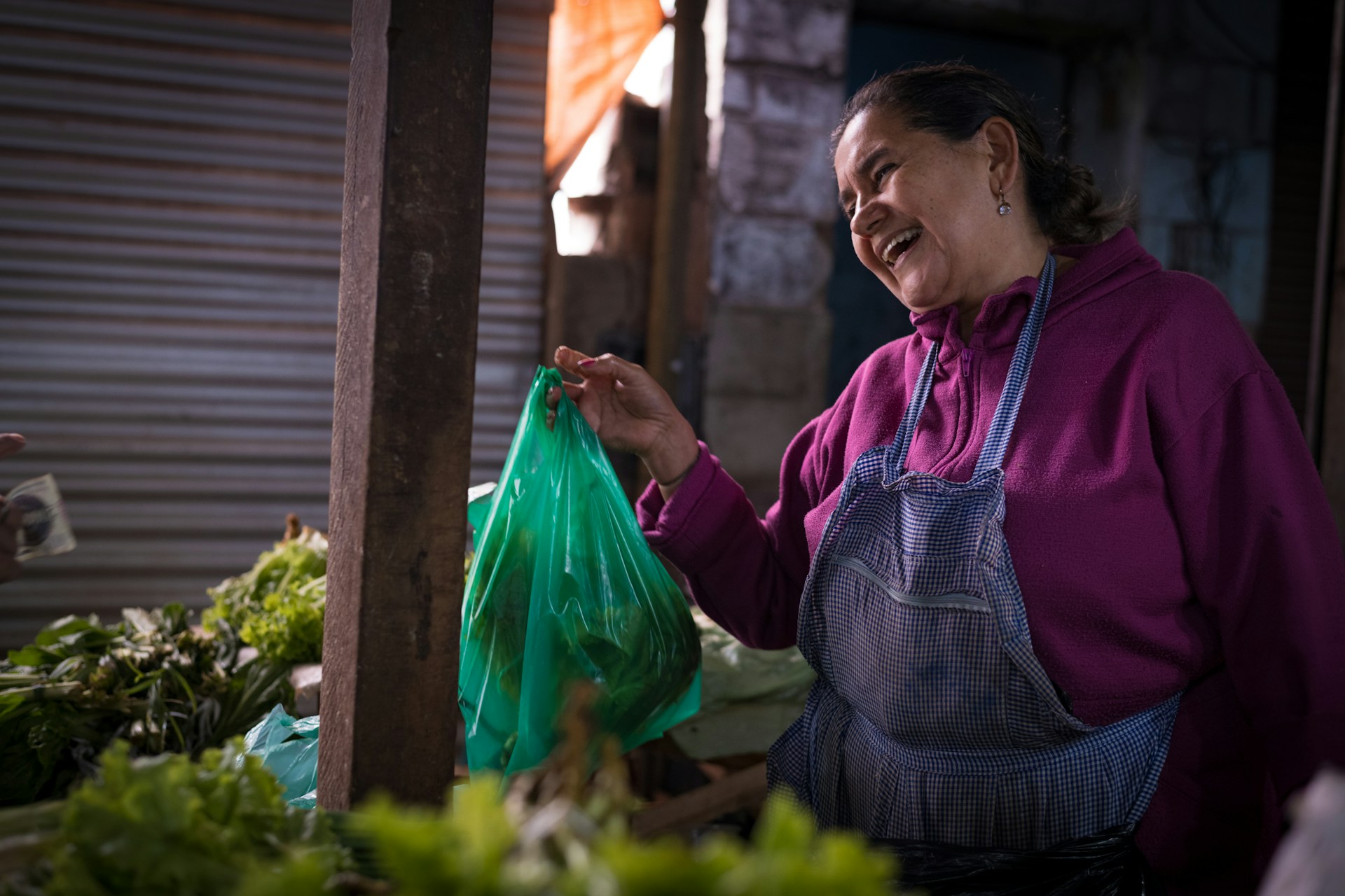 A woman laughs while holding a grocery bag.