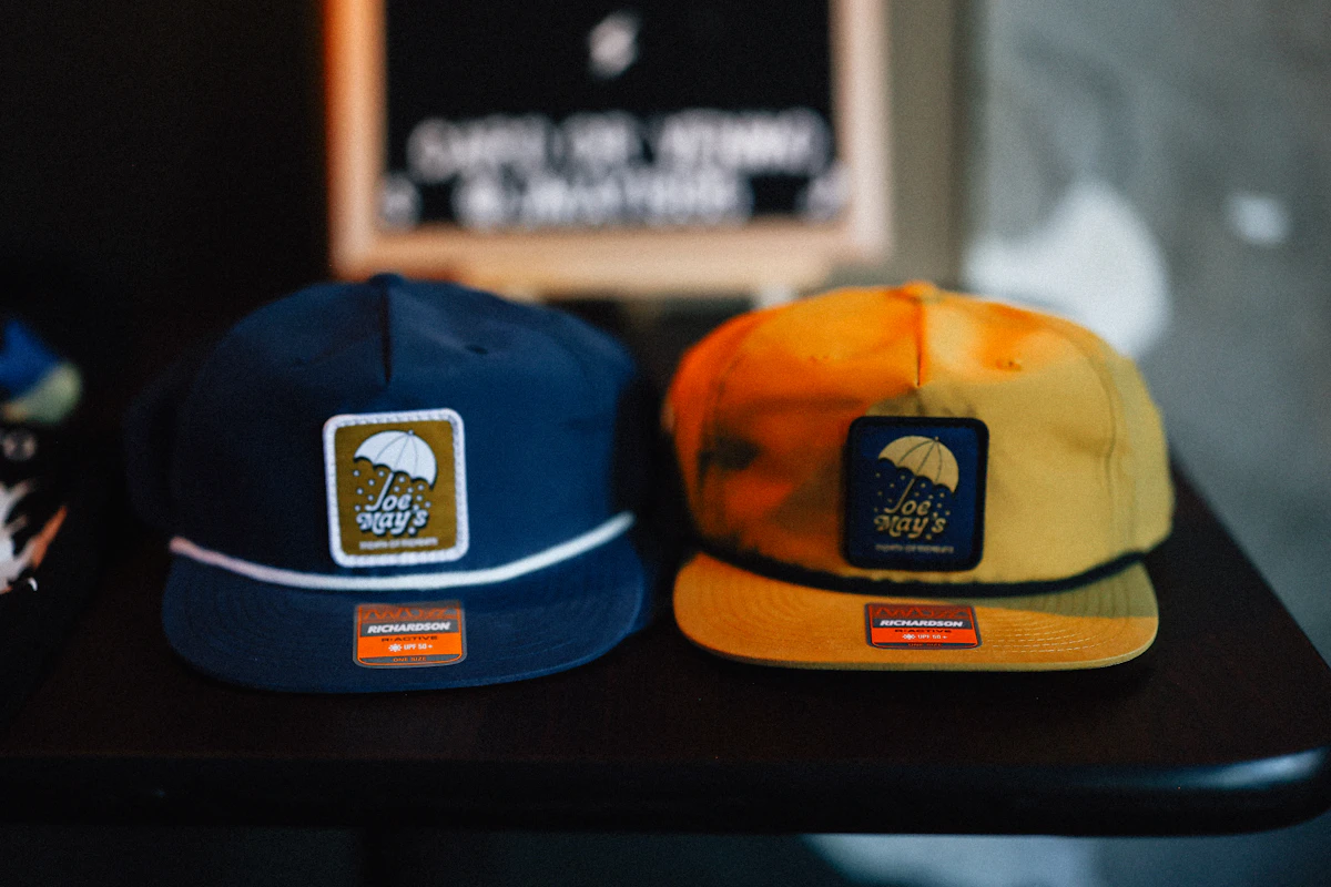 Two branded caps placed side by side showcasing colourful embroidered patches