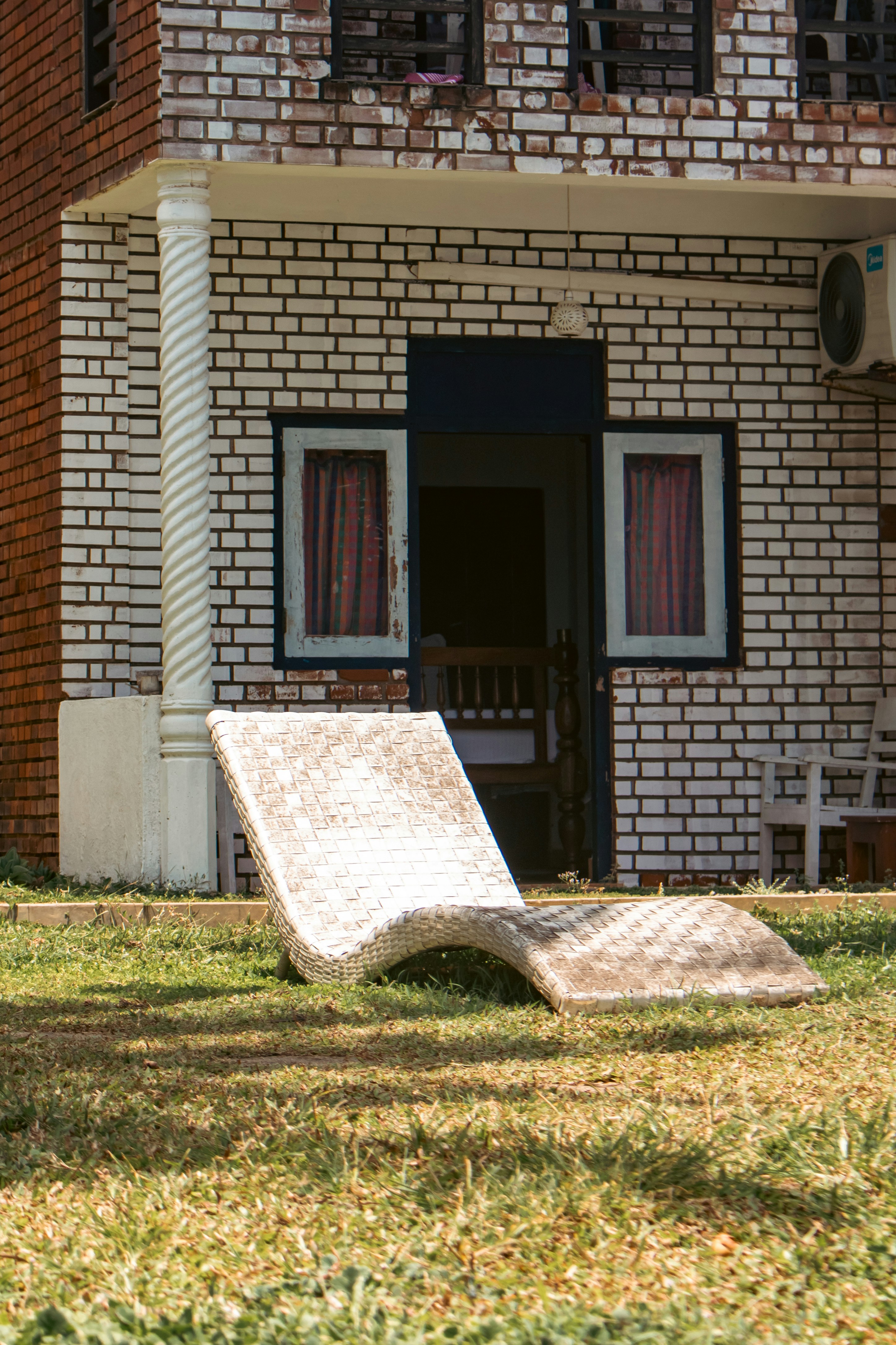 Lounge chair sits in front of a brick building.