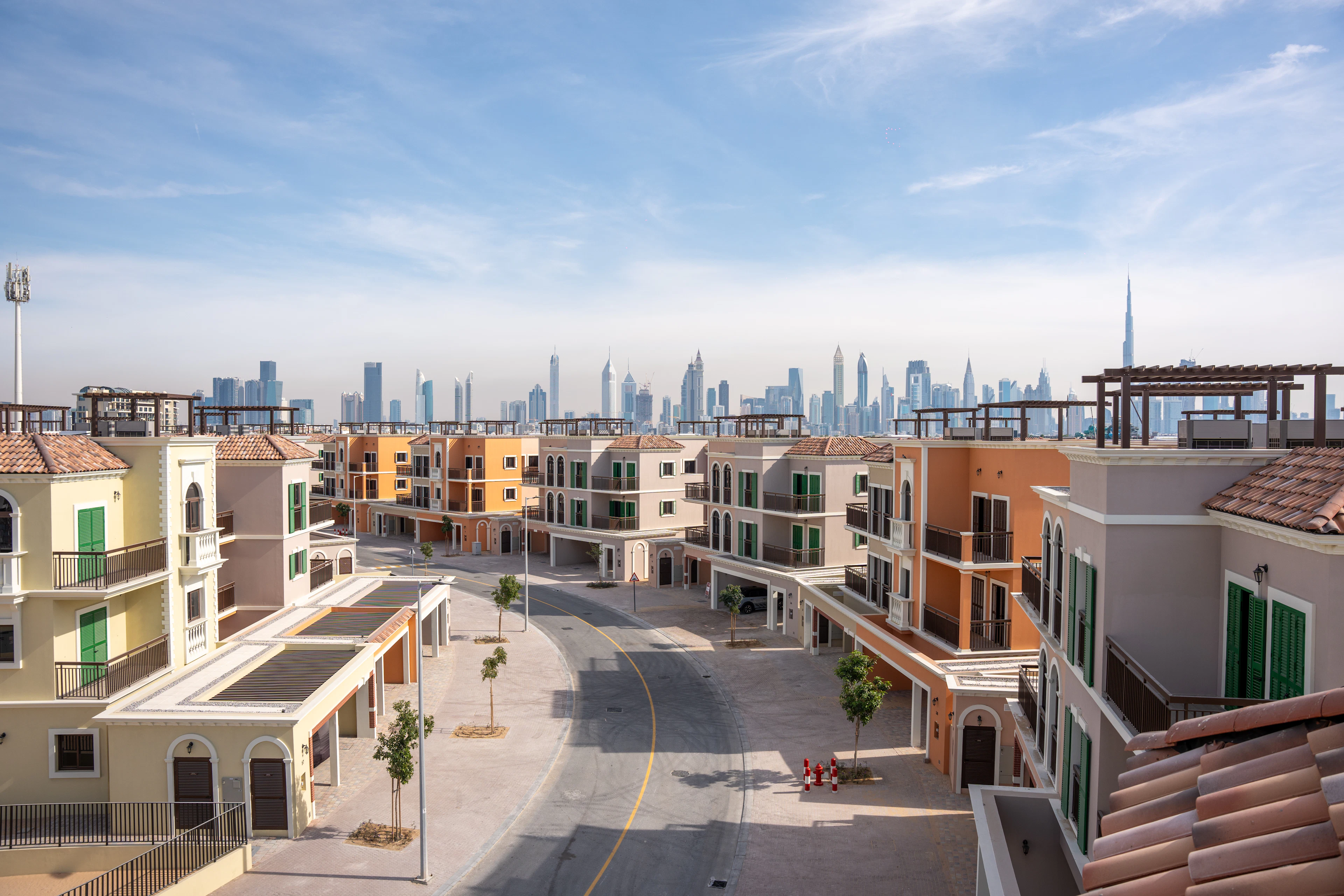 Low-rise residential community with a city skyline beyond — Townhouses in Sharjah