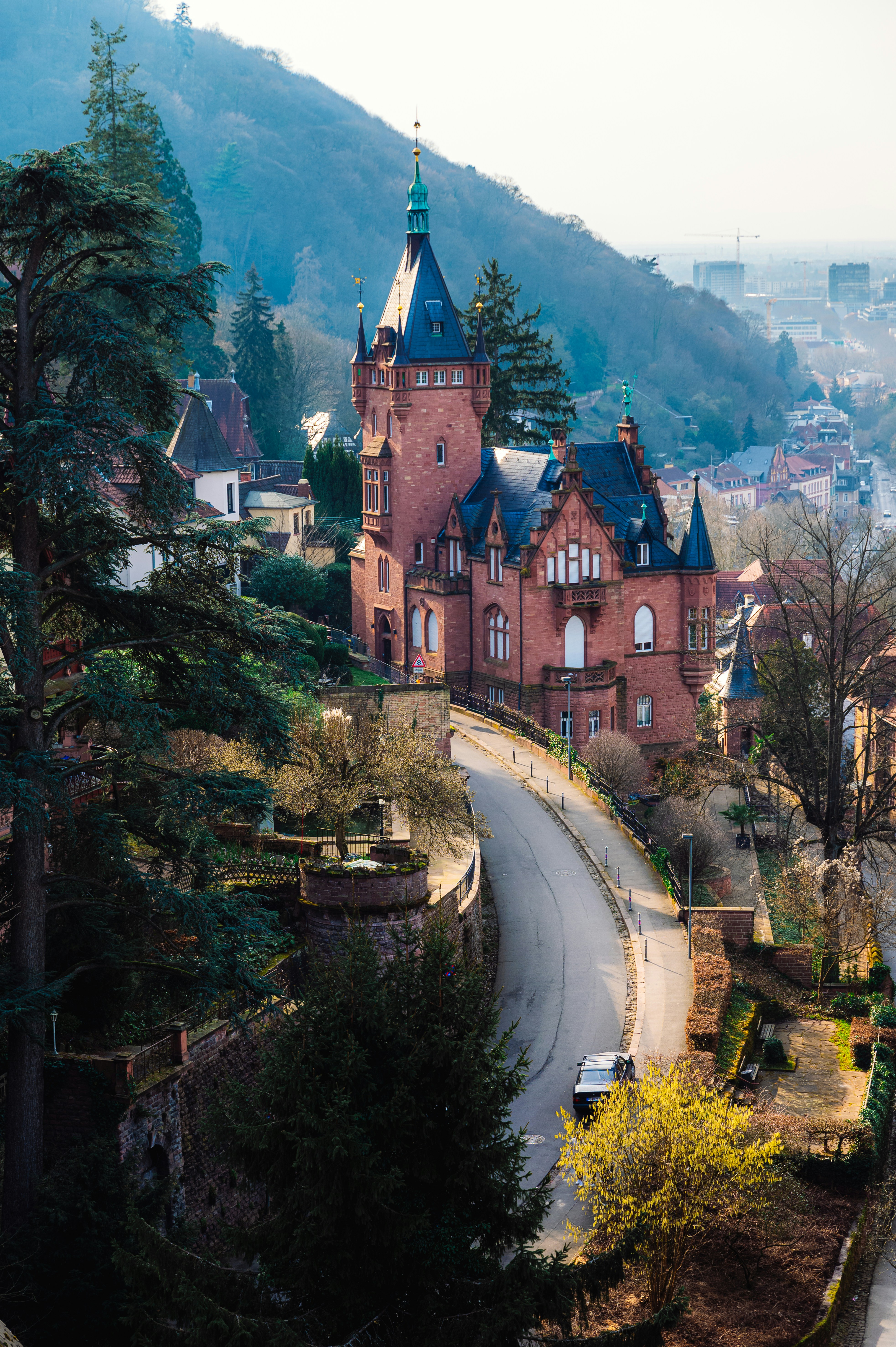 A beautiful red building sits atop a winding road.
