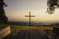 A cross stands on a hill overlooking the scenery.