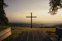 A cross stands on a hill overlooking the scenery.