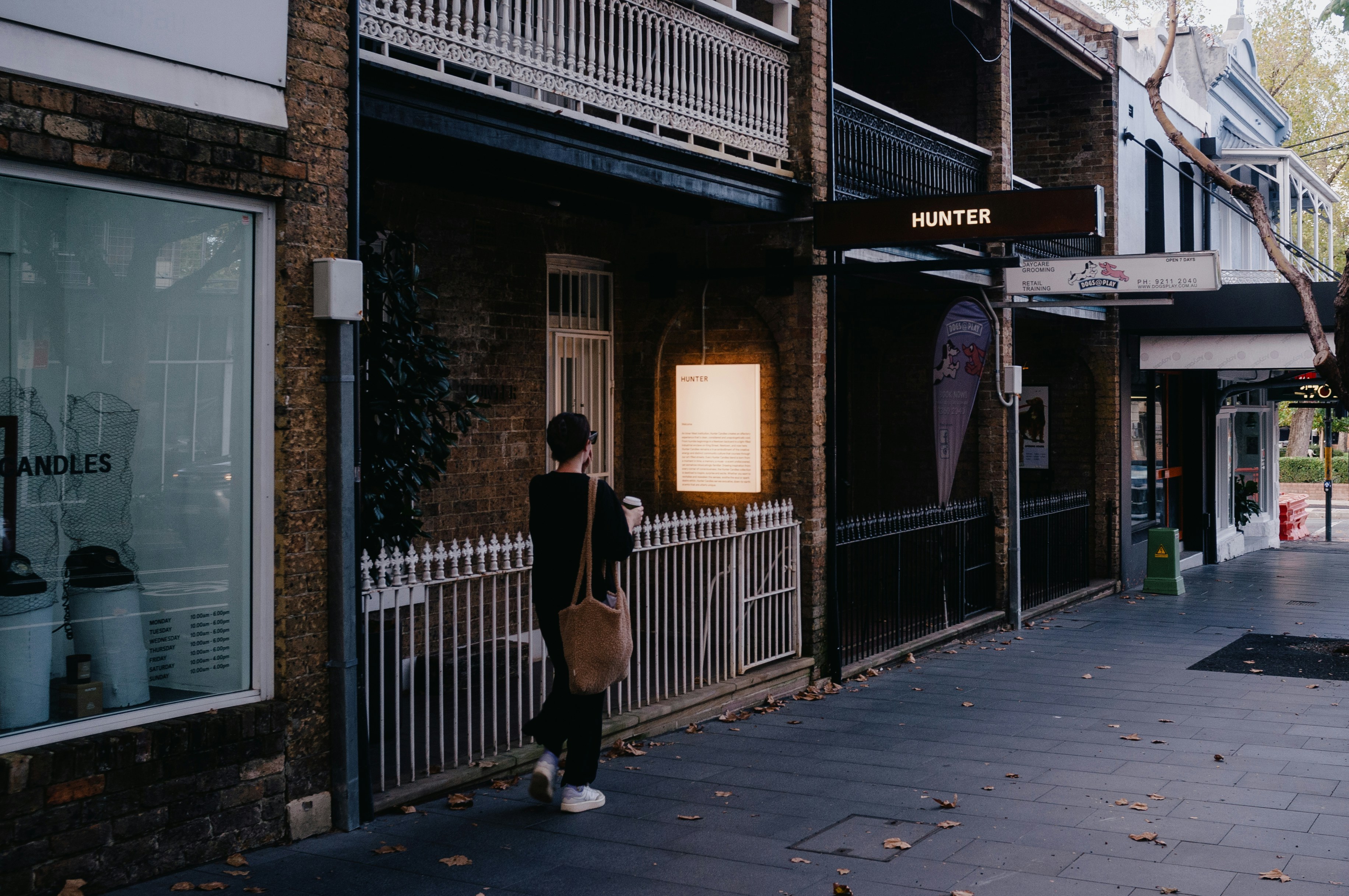 A person stands outside a restaurant on a street.