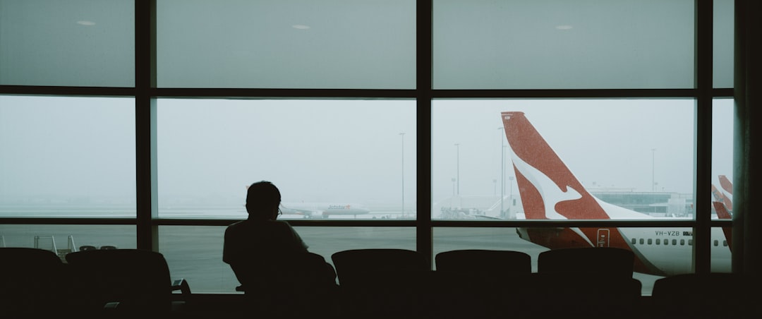A person waits in an airport, watching a plane.,