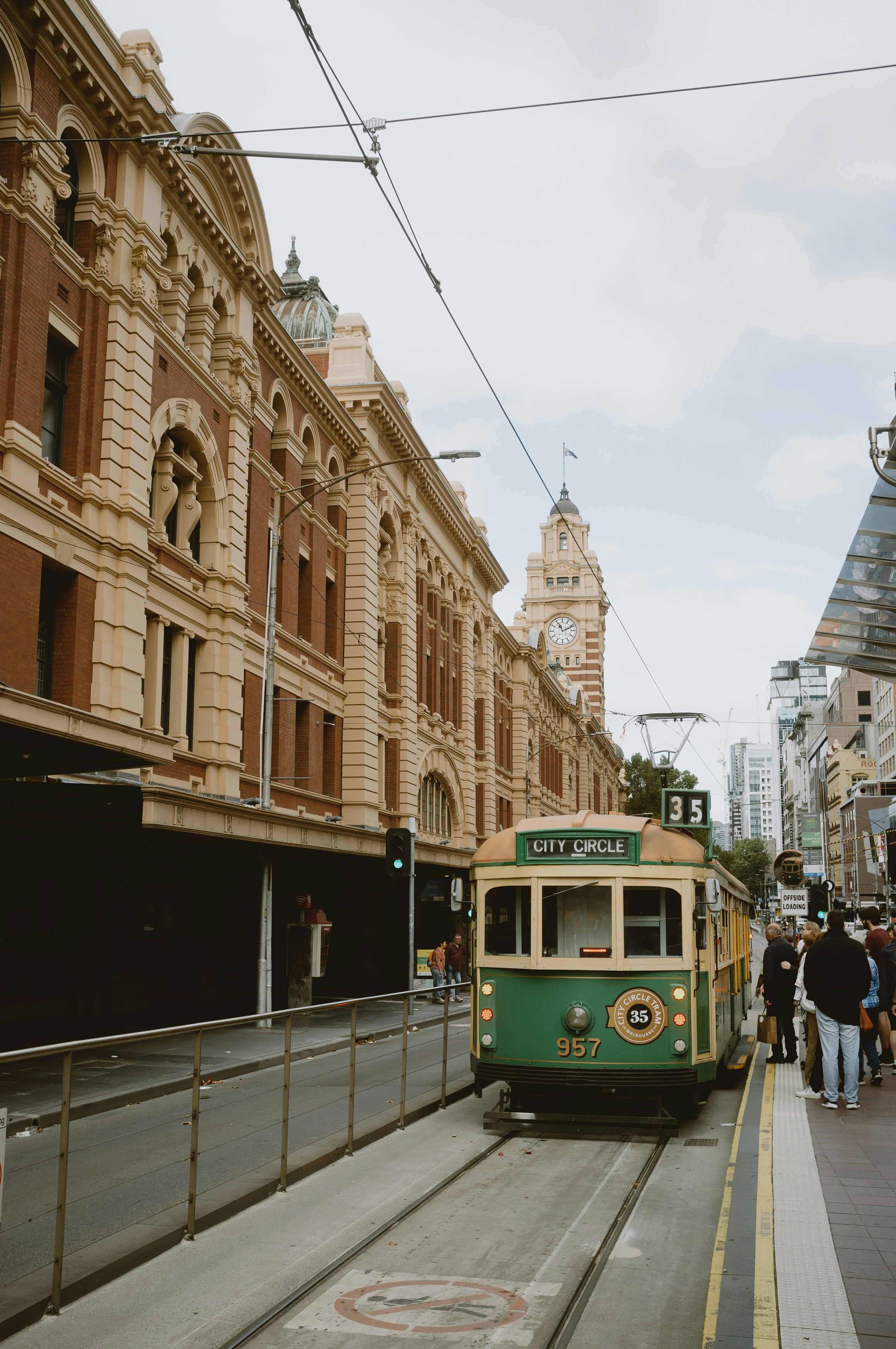 Eine grüne Straßenbahn fährt an einem großen Gebäude vorbei.