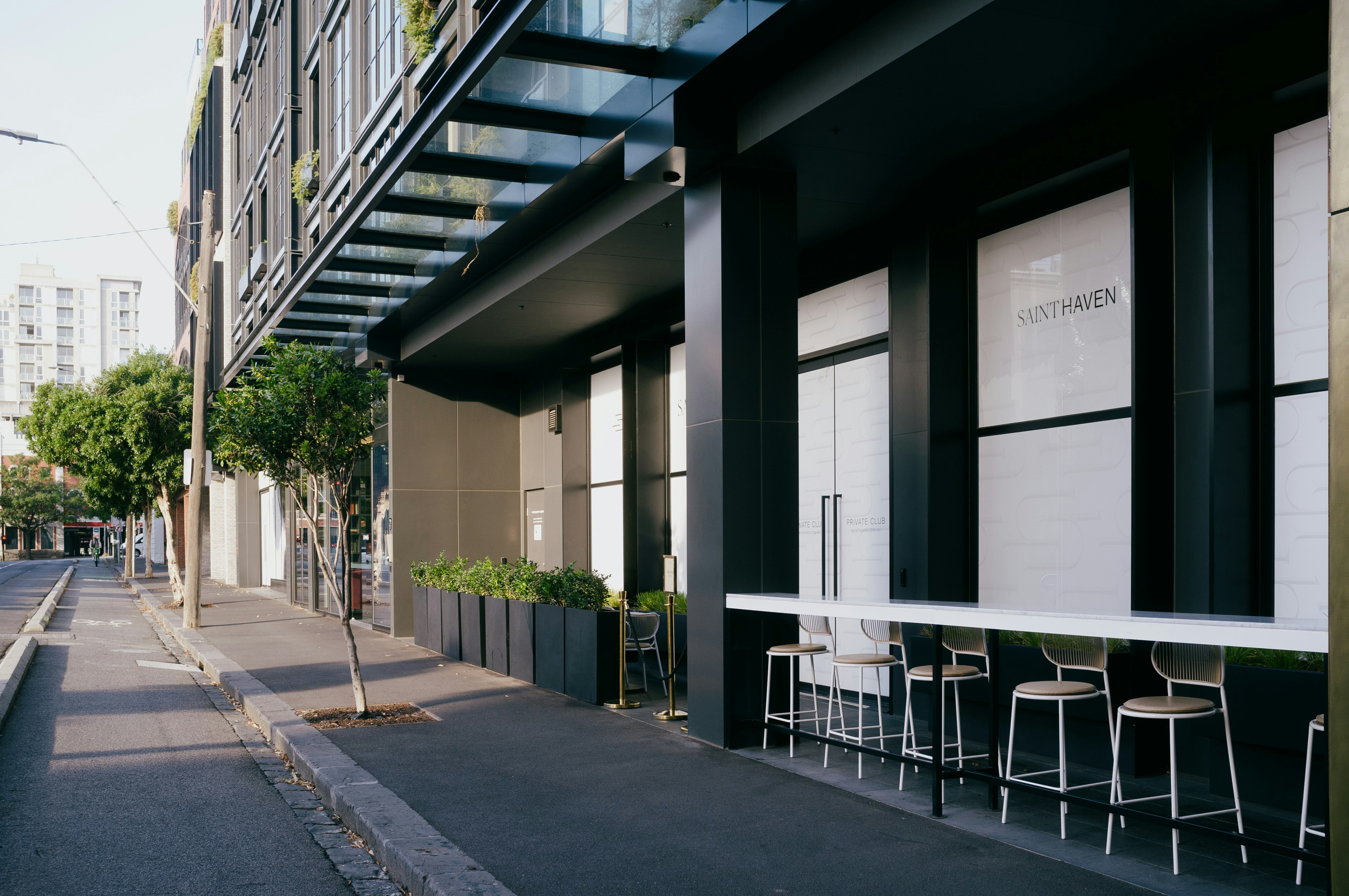 Modern building exterior with outdoor seating along a street.
