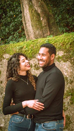 A smiling couple embraces each other outdoors.